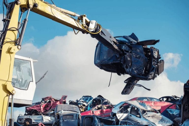 Crane lifting a crushed car body at a recycling yard