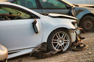 White car with heavy front-end accident damage and a broken bumper